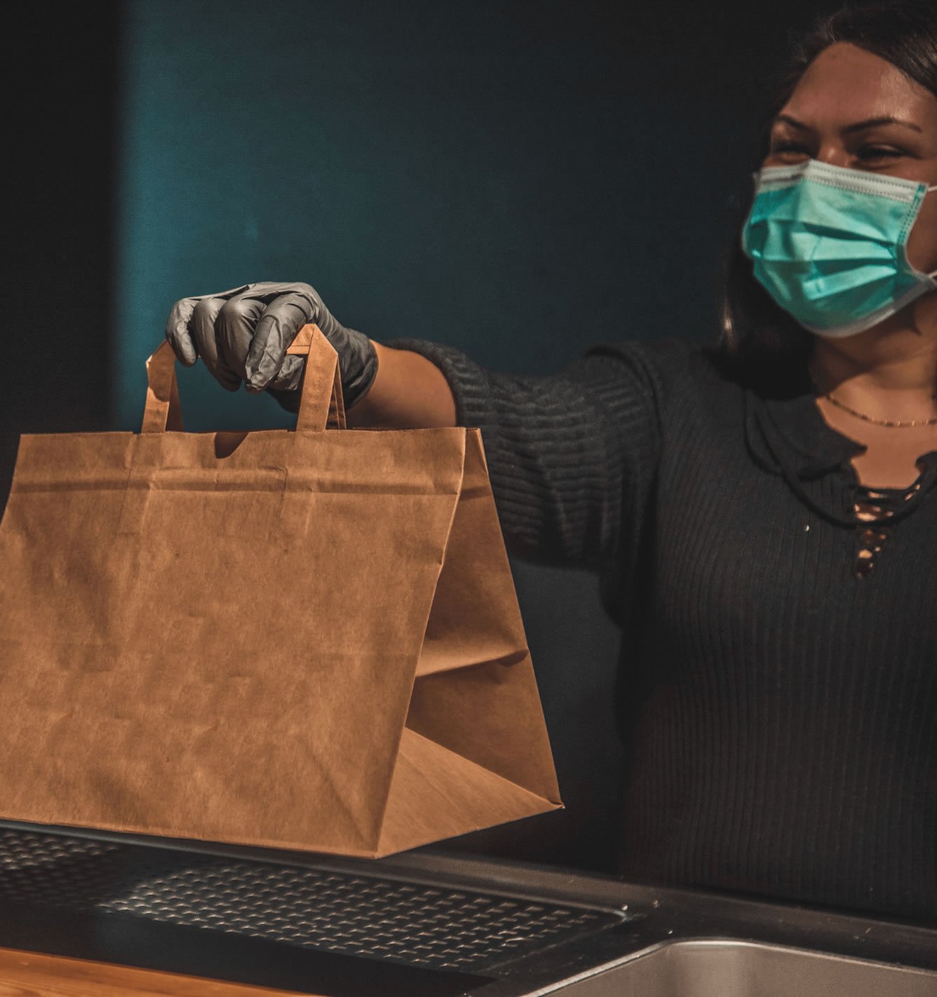woman wearing a mask offering takeaway service